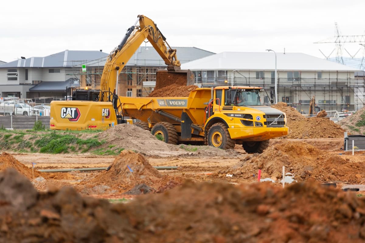 Yellow excavator loading dirt into a dump truck at a construction site